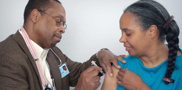 African American woman getting Covid vaccine from African American male doctor