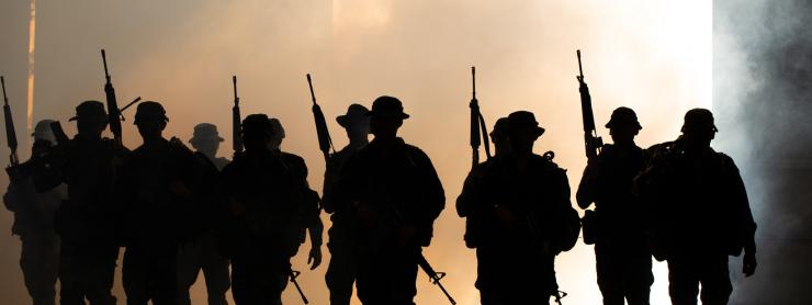 silhouette of soldiers walking through smoke